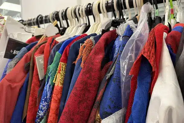 Colorful fabric samples and garments hanging on a rack in a fashion design studio.