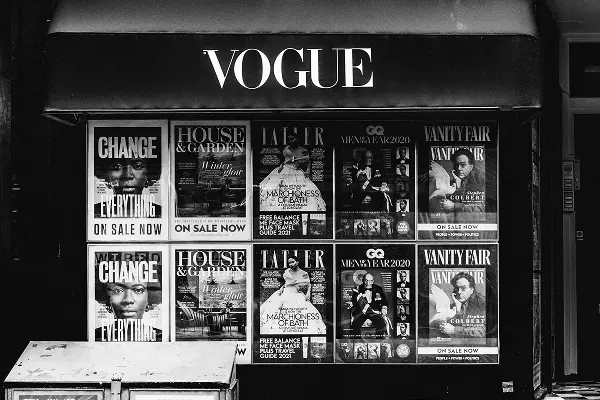 Black and white storefront display with Vogue sign and various magazine covers in the window.