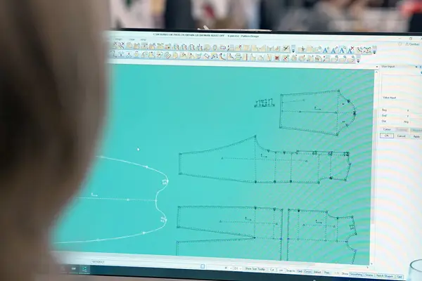 Person viewing digital garment pattern designs on a computer screen using fashion design software.
