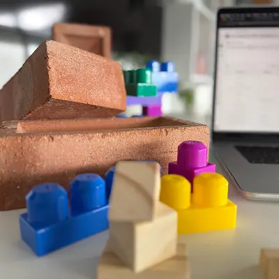 Colorful toy blocks and bricks next to a laptop, symbolizing system modularity and configurability.
