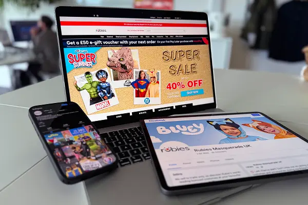 Digital marketing assets displayed on smartphone, laptop, and tablet screens featuring a costume brand’s promotional campaign.