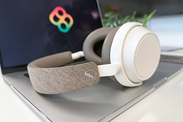 Modern headphones resting on a laptop with the Bombiix logo displayed on the screen.