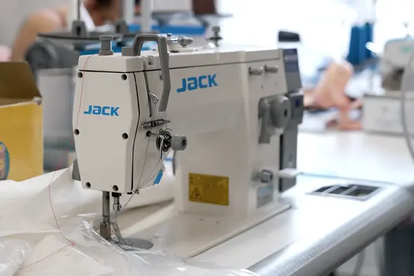 Industrial sewing machine labeled "JACK" in a textile production workspace.