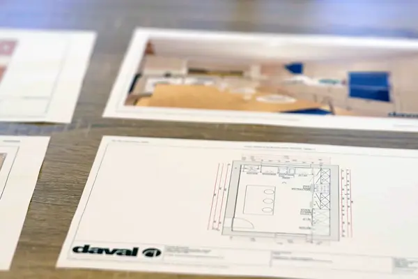 Technical specification sheets and design renders laid out on a table, showcasing product planning documentation.