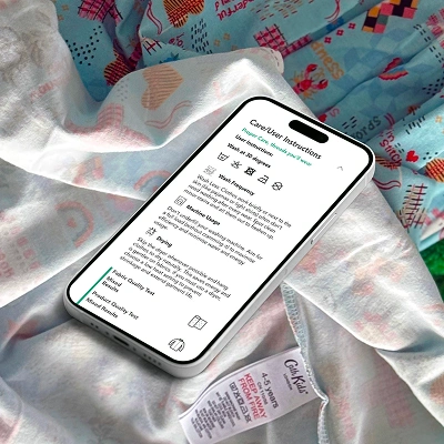 Smartphone displaying digital care and user instructions for a textile product, placed on a patterned fabric background.