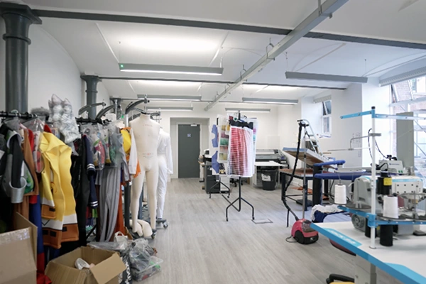 Fashion design studio with mannequins, sewing machines, garment racks, and fabrics.