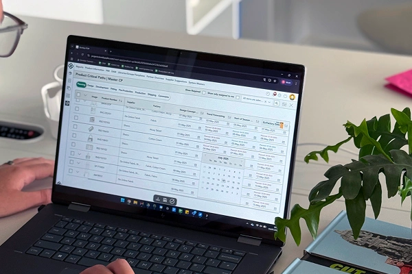 Person using a laptop to manage product critical path data in a PLM software interface.