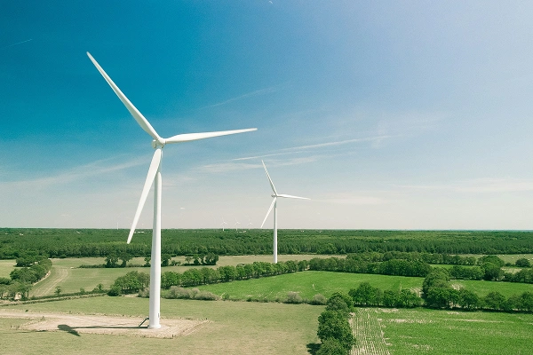 Wind turbines in a green rural landscape under a clear blue sky, symbolising renewable energy and sustainability.