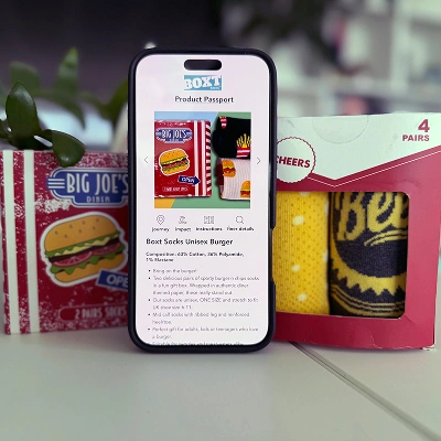 Smartphone showing a digital product passport for socks, displayed next to vibrant packaging from Big Joe’s.