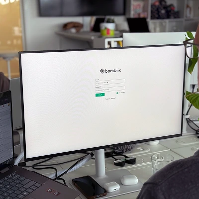 User login screen for Bombiix platform displayed on a desktop monitor in a modern office.