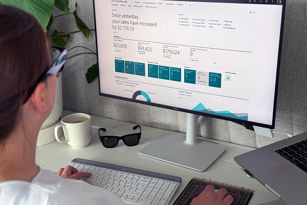 Person reviewing sales analytics dashboard on a desktop monitor in a modern workspace.