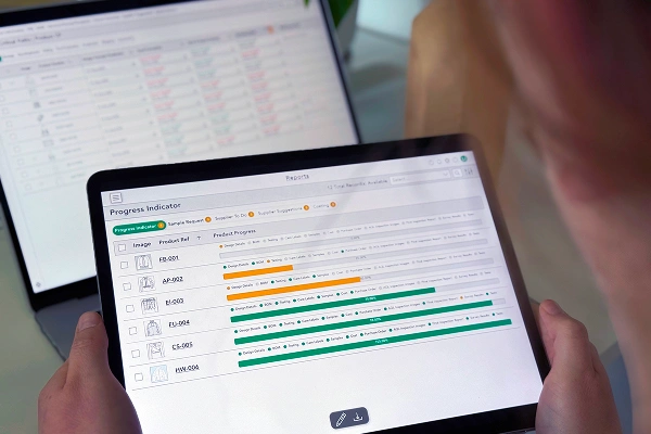 Person viewing product progress indicators on a tablet screen using Bombiix PLM software.