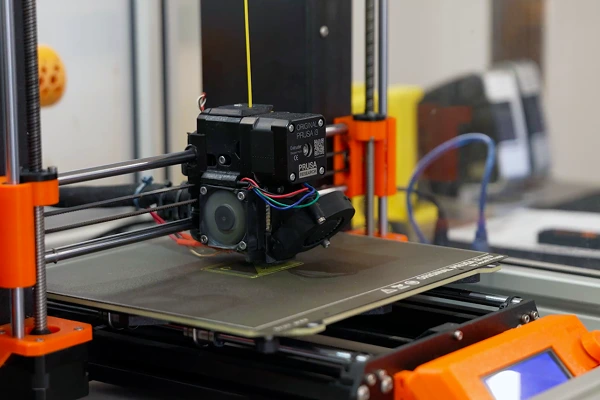 Close-up of a 3D printer actively producing a component, representing innovation in manufacturing.