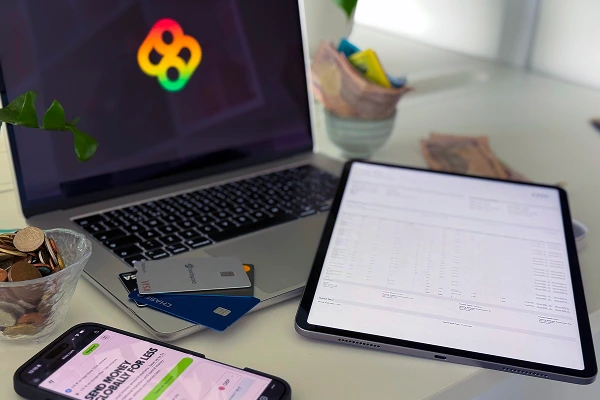 Digital finance and procurement tools displayed on multiple devices with coins, cards, and cash nearby.