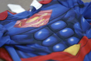 Close-up of a padded children's superhero costume with a printed red and yellow emblem on a blue muscle suit.